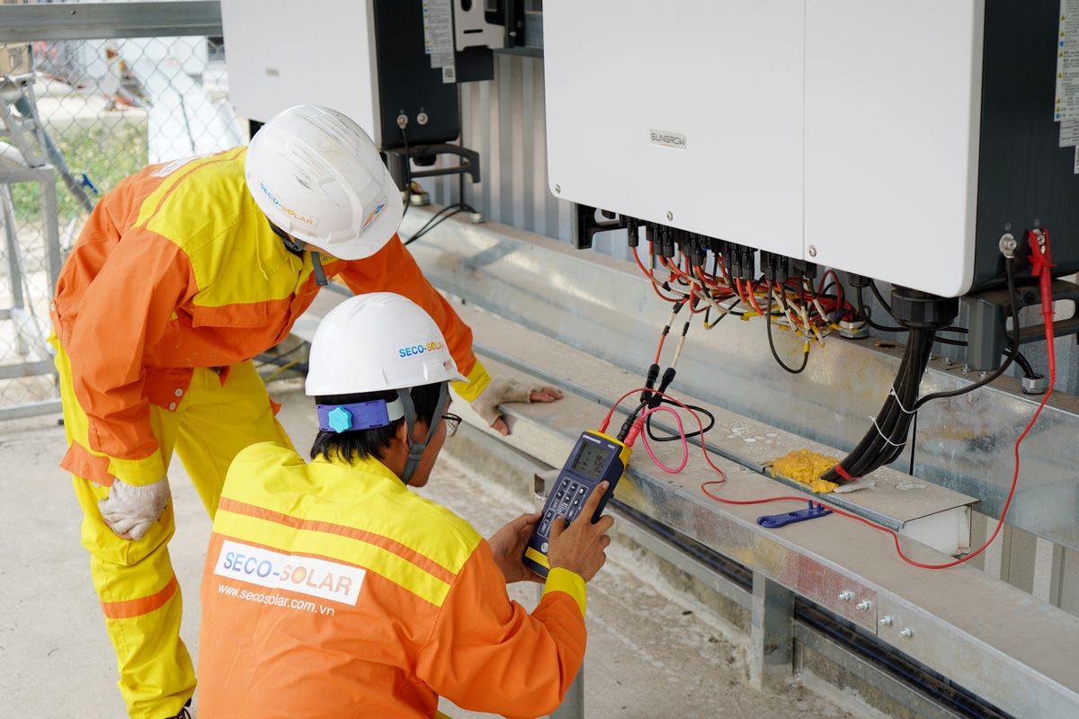 Two engineers testing a solar power system with a meter