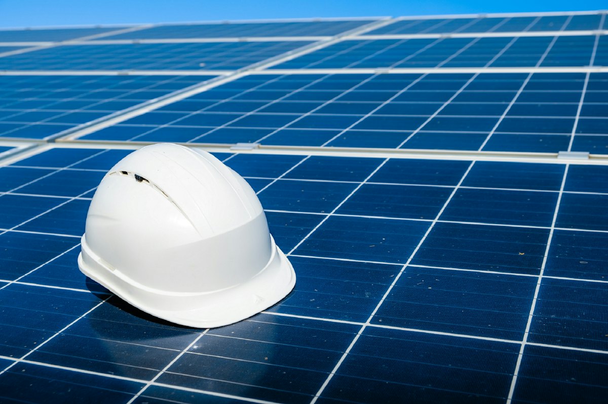 White safety hard hat resting on a blue solar panel