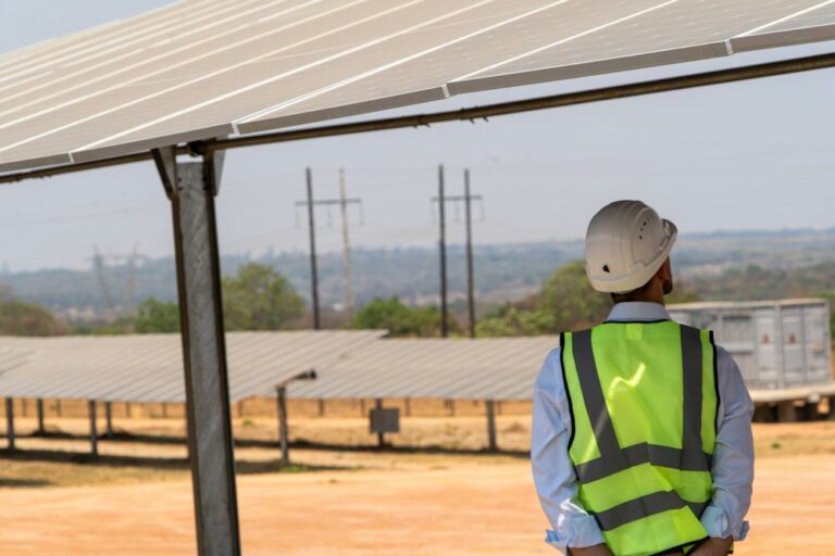 Engineer in a safety vest beside a mounted solar panel frame