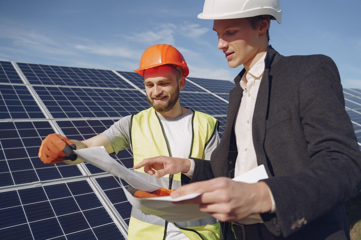 Two engineers in hard hats discussing a solar project on site