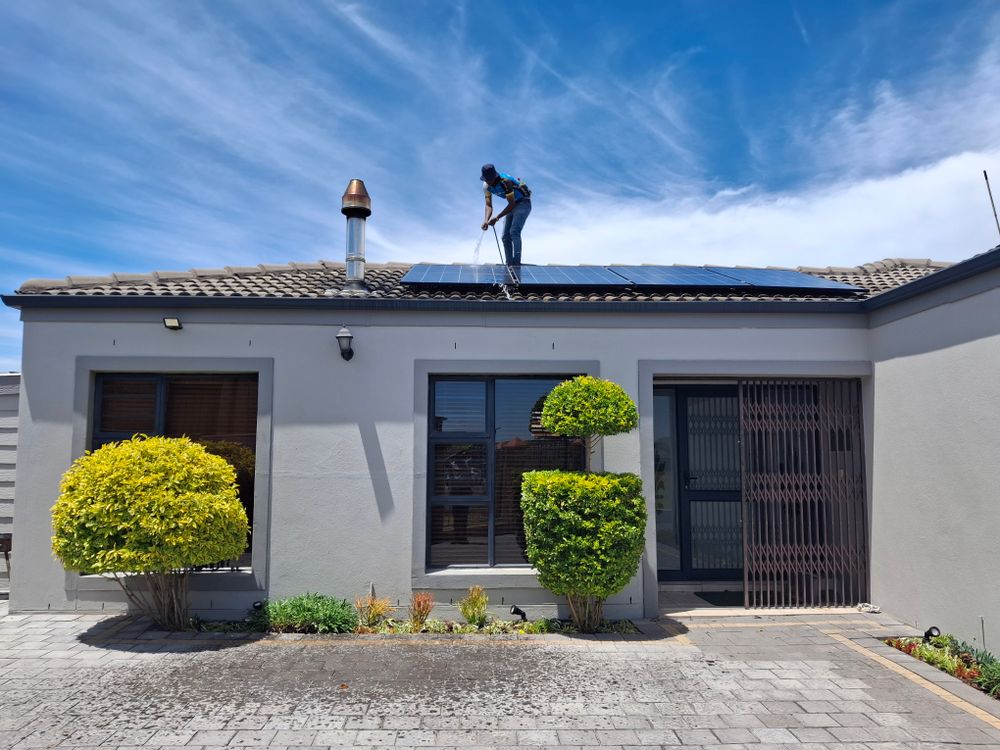 Technician maintaining solar panels on a house roof