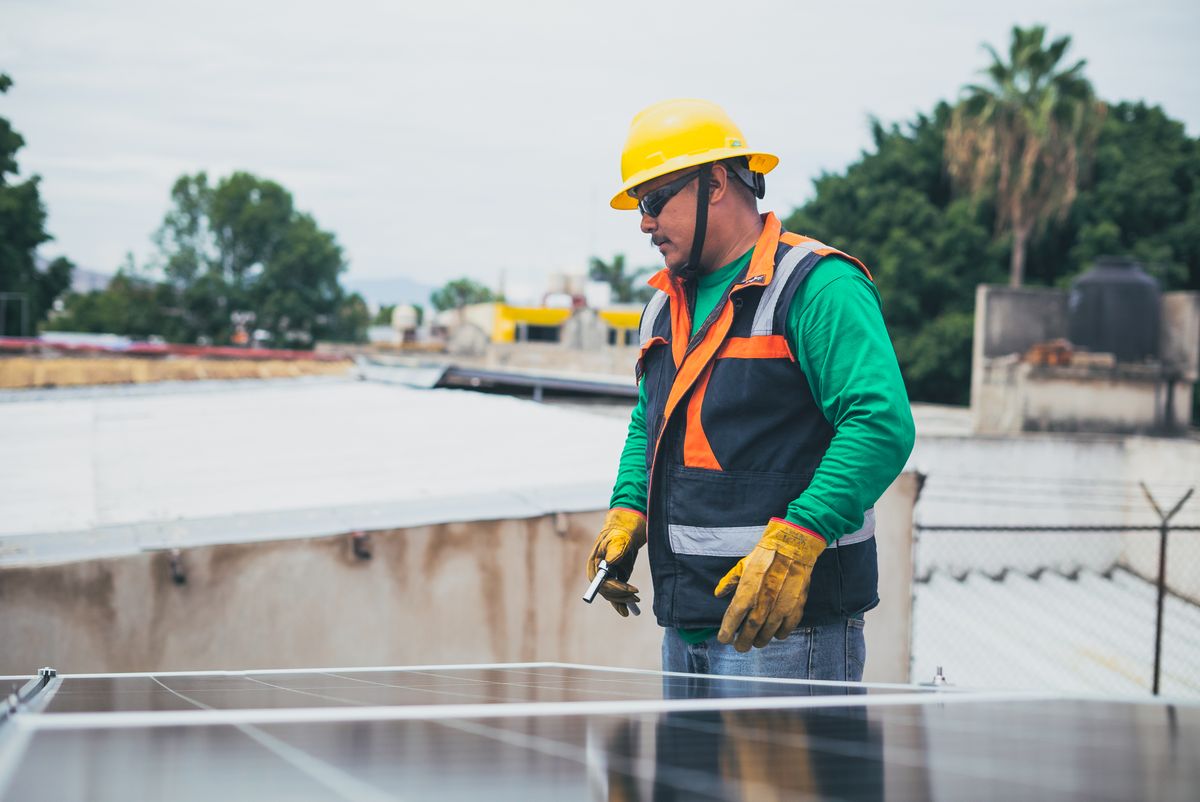 Solar technician in protective gear inspecting rooftop panels