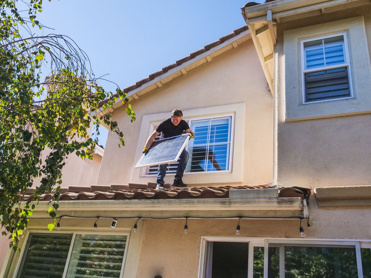 Solar technician installing panels on the roof of a house