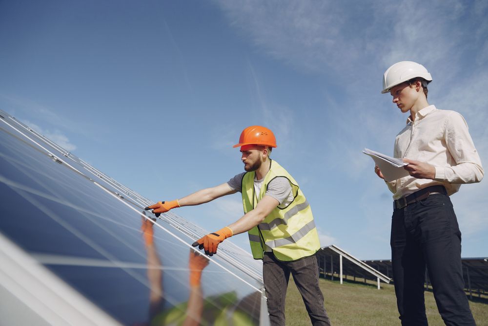 Solar technician in a yellow vest and hard hat explaining an installation