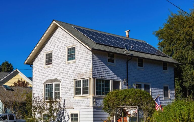 Two-storey home with solar panels on its roof under a clear sky